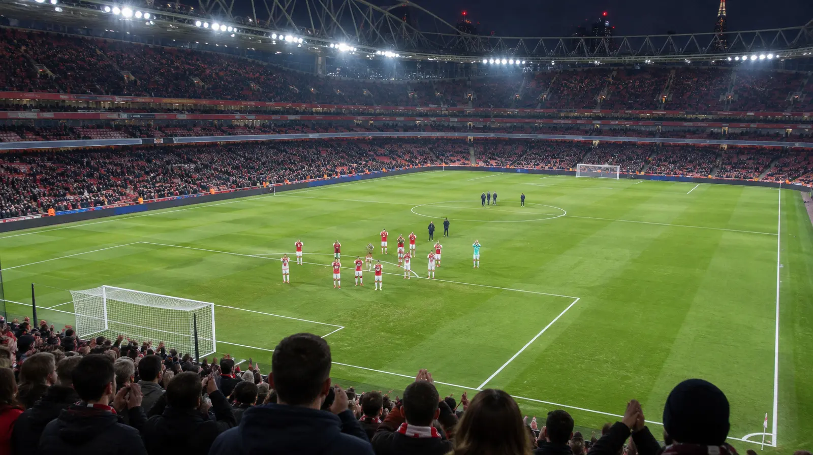 Spelare applåderar publiken efter matchen i kvällsljus på en stor arena